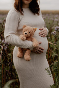 Romantisches Babybauchfoto zwischen blühenden Blumen